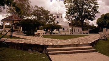 Un edificio histórico con un campanario, rodeado de árboles y un sendero de piedra.
