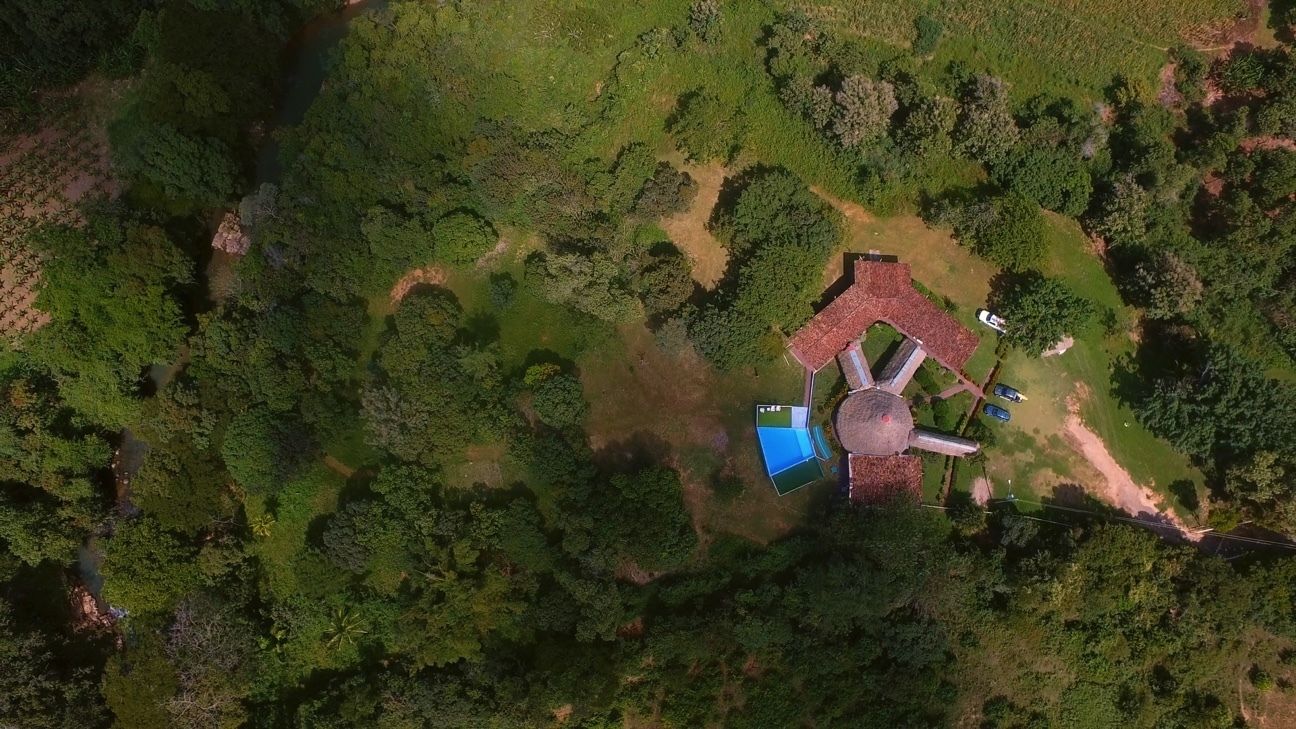 An aerial view of a property with a central circular structure surrounded by greenery and a few buildings.