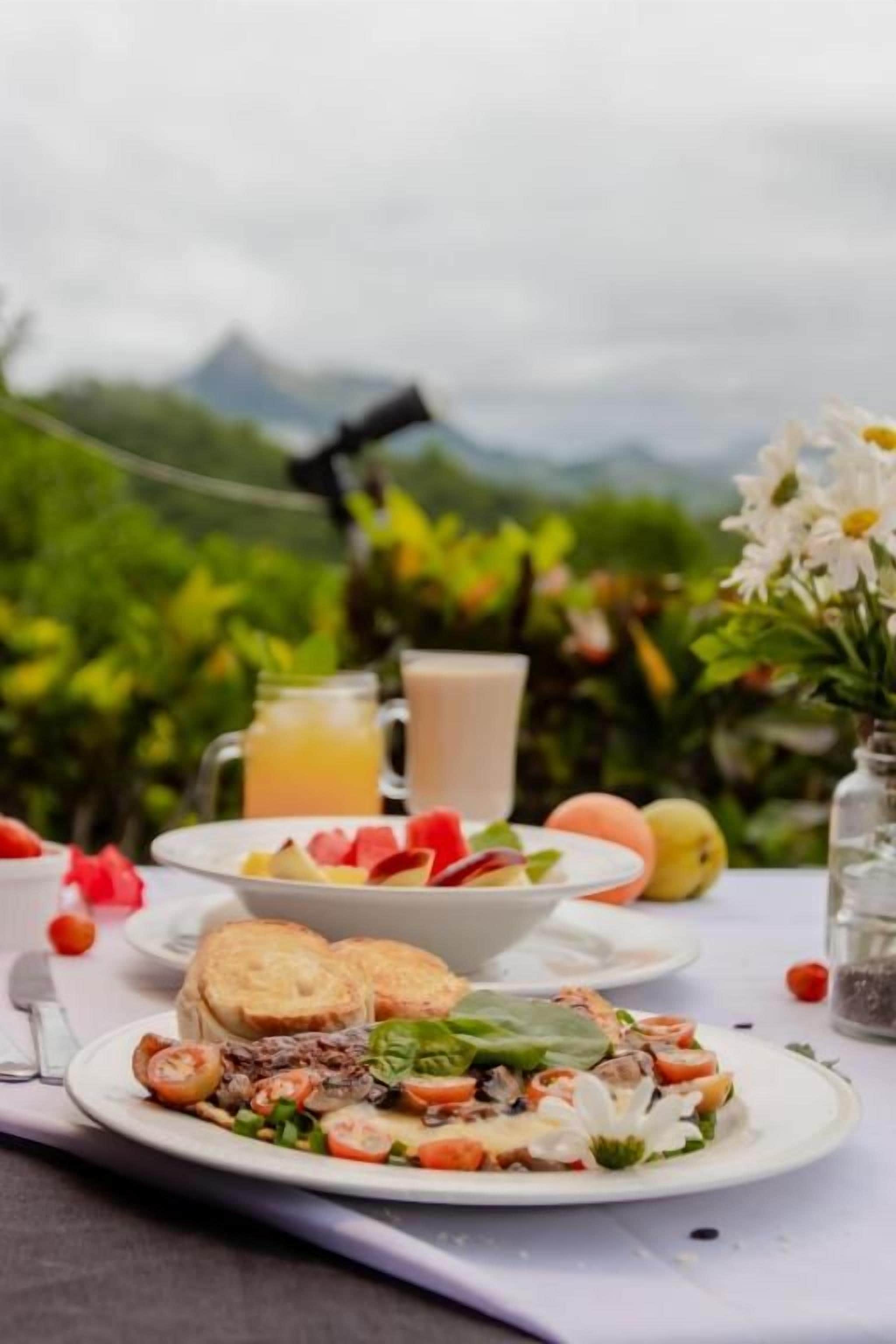 Una mesa lista para el desayuno con tostadas, fruta y una ensalada, con una vista panorámica al fondo.