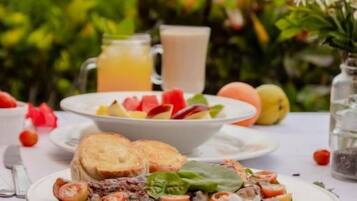 Una mesa lista para el desayuno con tostadas, fruta y una ensalada, con una vista panorámica al fondo.
