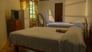 Un dormitorio con dos camas, un aparador, un televisor y una ventana con cortinas.