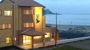 A two-story building with a yellow facade and a brick section, featuring large windows and a visible sign with Japanese characters. - Yuukaro Showa (Kami)