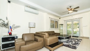 A modern living room with a brown leather sofa, a glass coffee table, and a decorative plant. - Platinum 3 bedrooms villa pool garden (Rawai)
