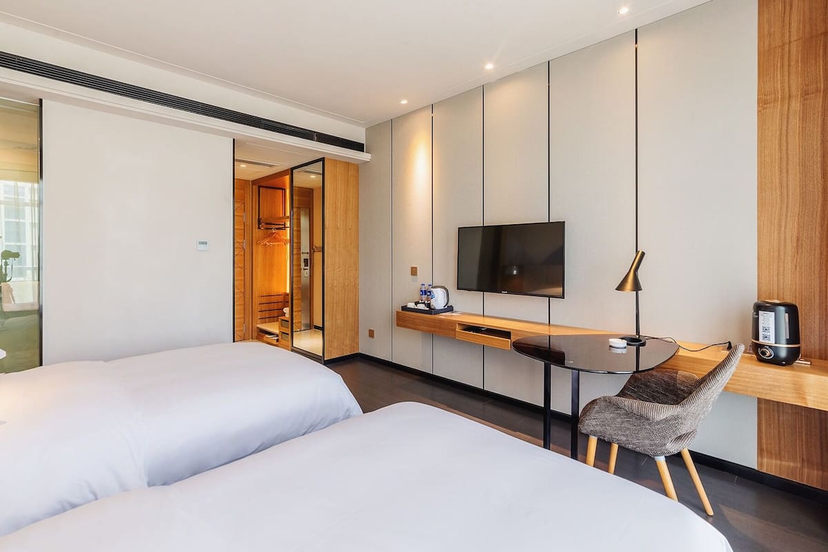 Une chambre d’hôtel avec deux lits, un bureau doté d’un téléviseur à écran plat, une chaise et une machine à café.