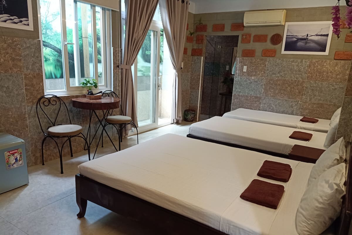 Een hotelkamer met twee bedden, een eettafel met stoelen, een koelkast en een raam met gordijnen.
