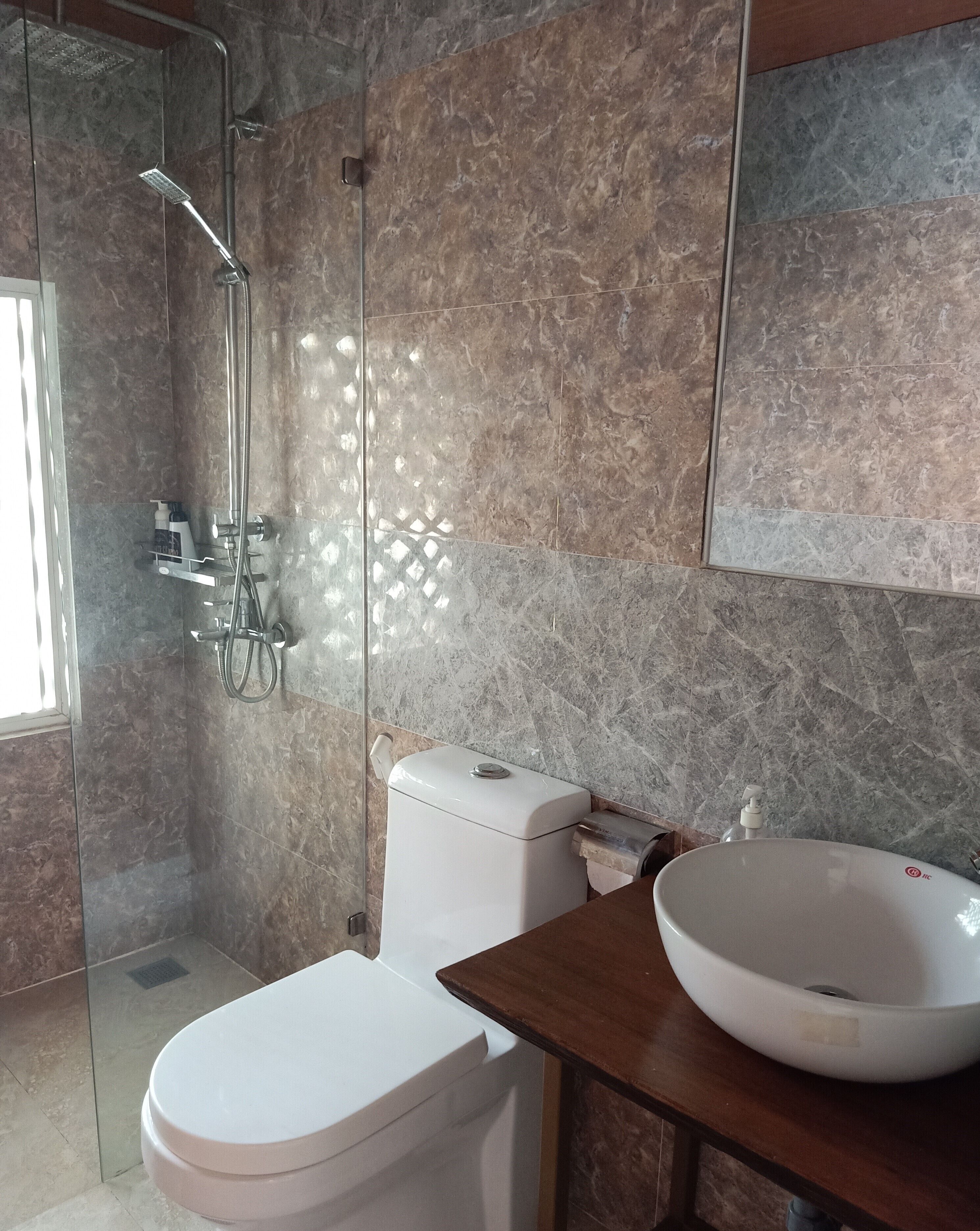 Un baño moderno con ducha de mampara de vidrio, inodoro blanco y un lavamanos grande en blanco.
