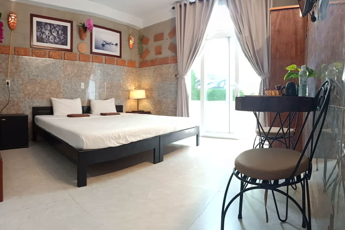 Een slaapkamer met een bed, nachtkastjes, een stoel en een raam met gordijnen.