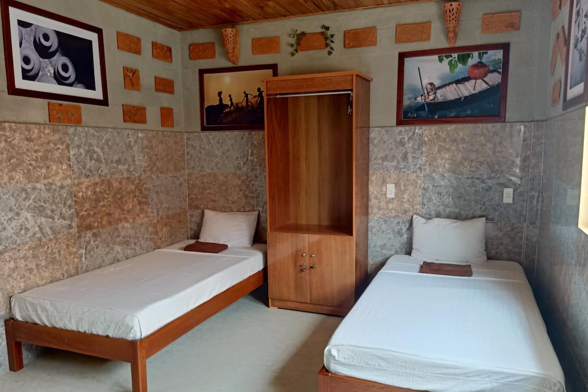 Een kamer met twee houten bedden, een houten garderobe en stenen muren.