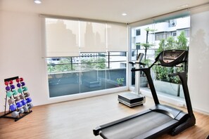 A modern gym with a treadmill, a weight rack, and a large window offering a city view. - The Kaze 34 Hotel and Serviced Residence (Bangkok)