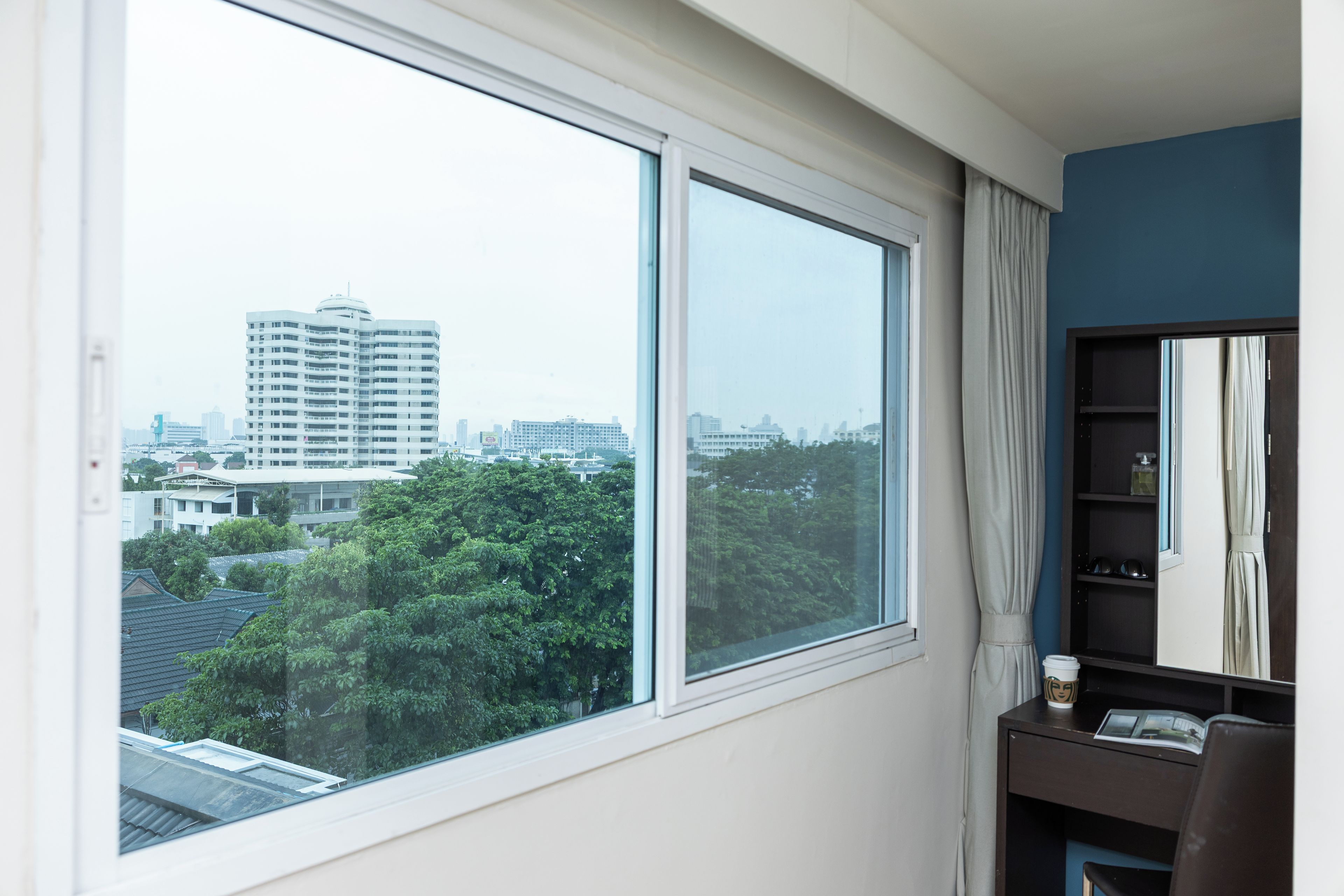 A room with a large window offering a view of a cityscape and trees.