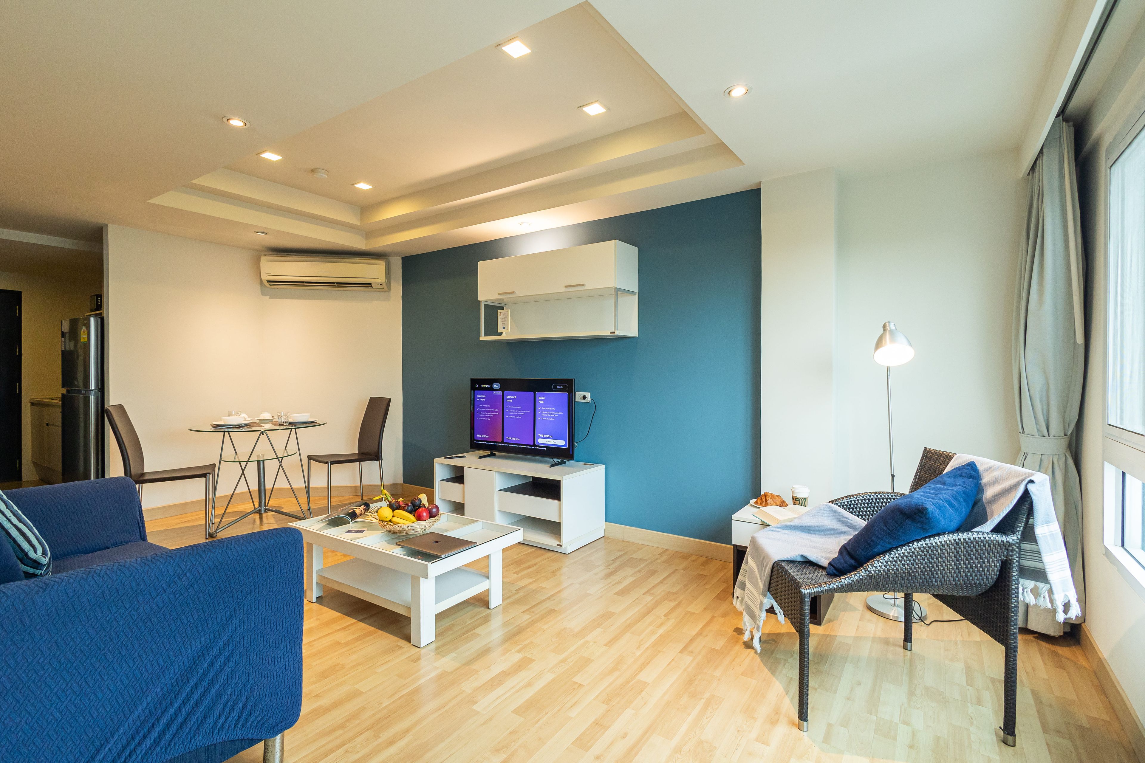 A modern living room with a flat-screen TV, a dining table, and seating.