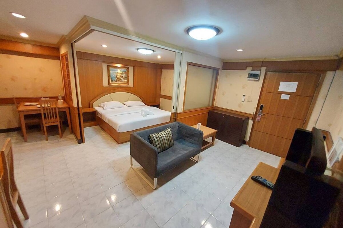Una habitación de hotel con cama, sofá, escritorio y televisión.