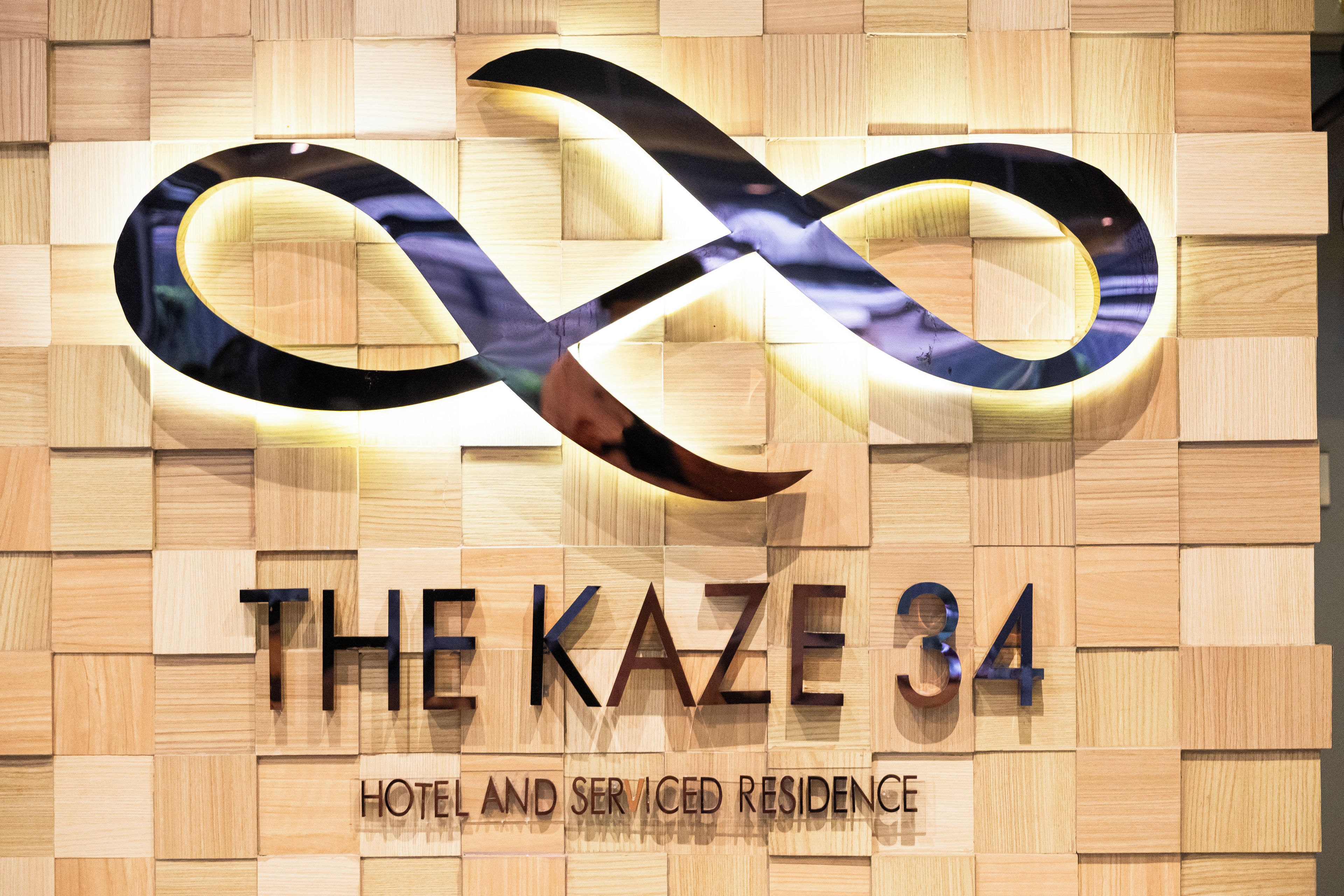 A hotel sign with an infinity symbol and the name 'THE KAZE 34' along with the words 'HOTEL AND SERISED RESIDENCE'.