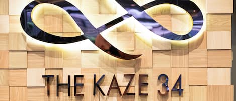 A hotel sign with an infinity symbol and the name 'THE KAZE 34' along with the words 'HOTEL AND SERISED RESIDENCE'.