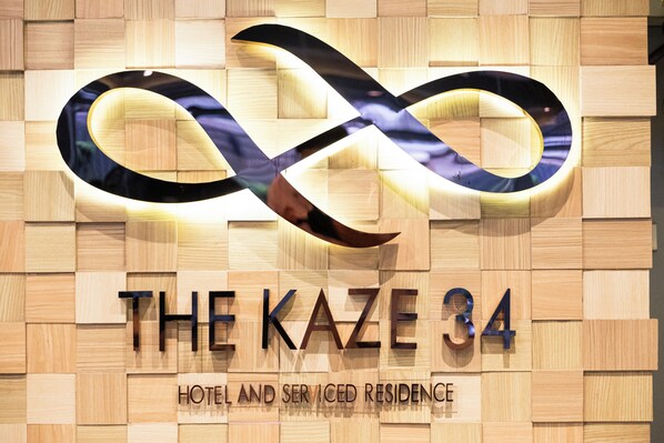 A hotel sign with an infinity symbol and the name 'THE KAZE 34' along with the words 'HOTEL AND SERISED RESIDENCE'.