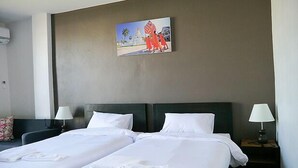 Una habitación de hotel con dos camas, un cuadro en la pared y dos lámparas de noche.