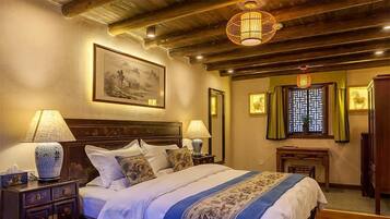 Un dormitorio tradicional con cama de madera, dos mesitas de noche con lámparas, un cuadro grande enmarcado en la pared y una ventana con celosía decorativa.