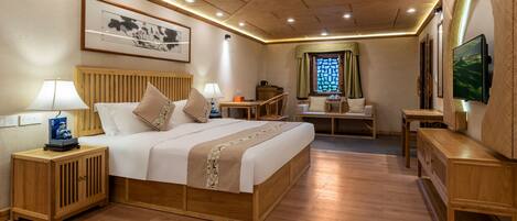 Une chambre d’hôtel avec un lit en bois, des tables de chevet, un bureau et un téléviseur.
