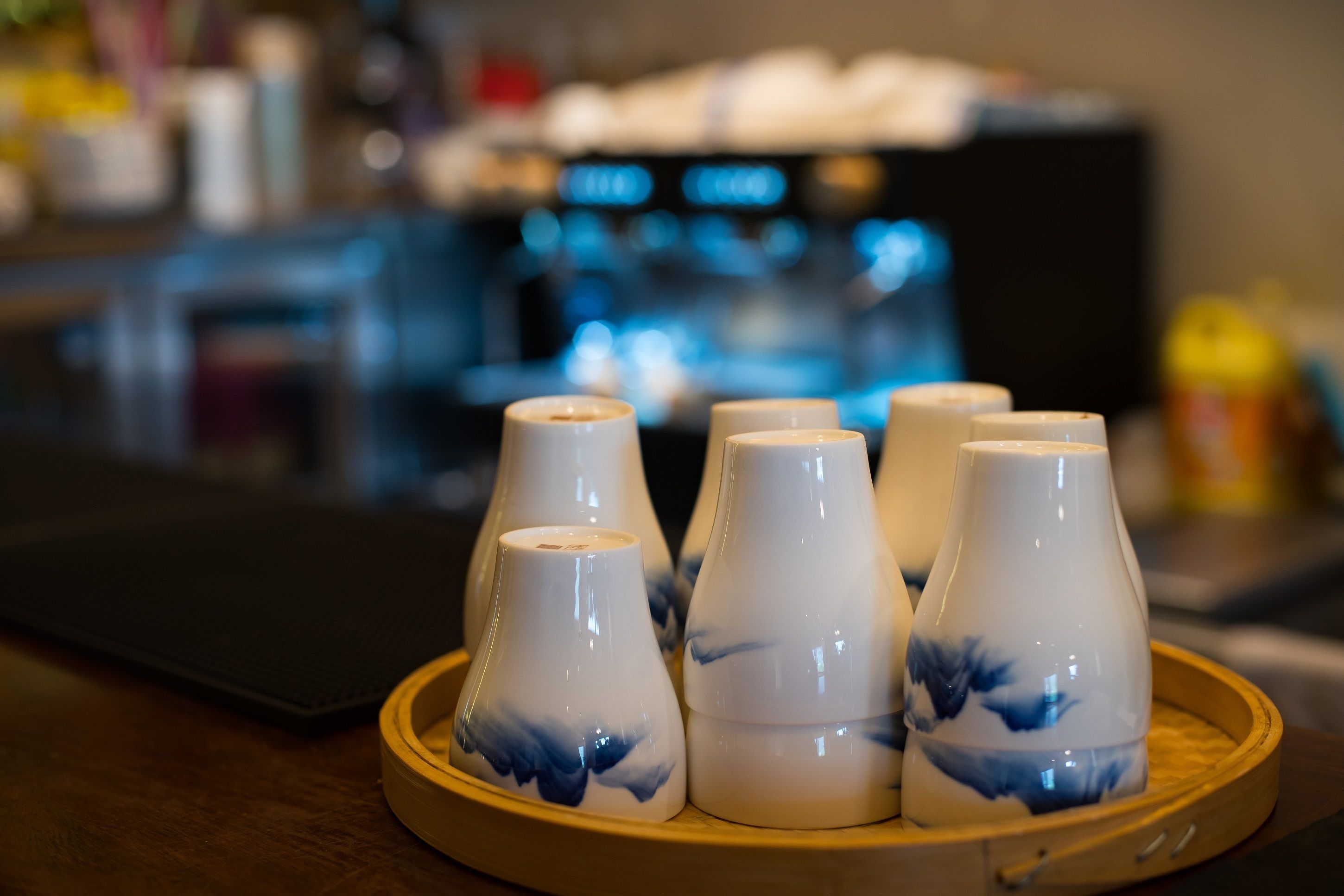 Una bandeja con seis tazas de cerámica blanca con diseños azules, sobre una superficie de madera.