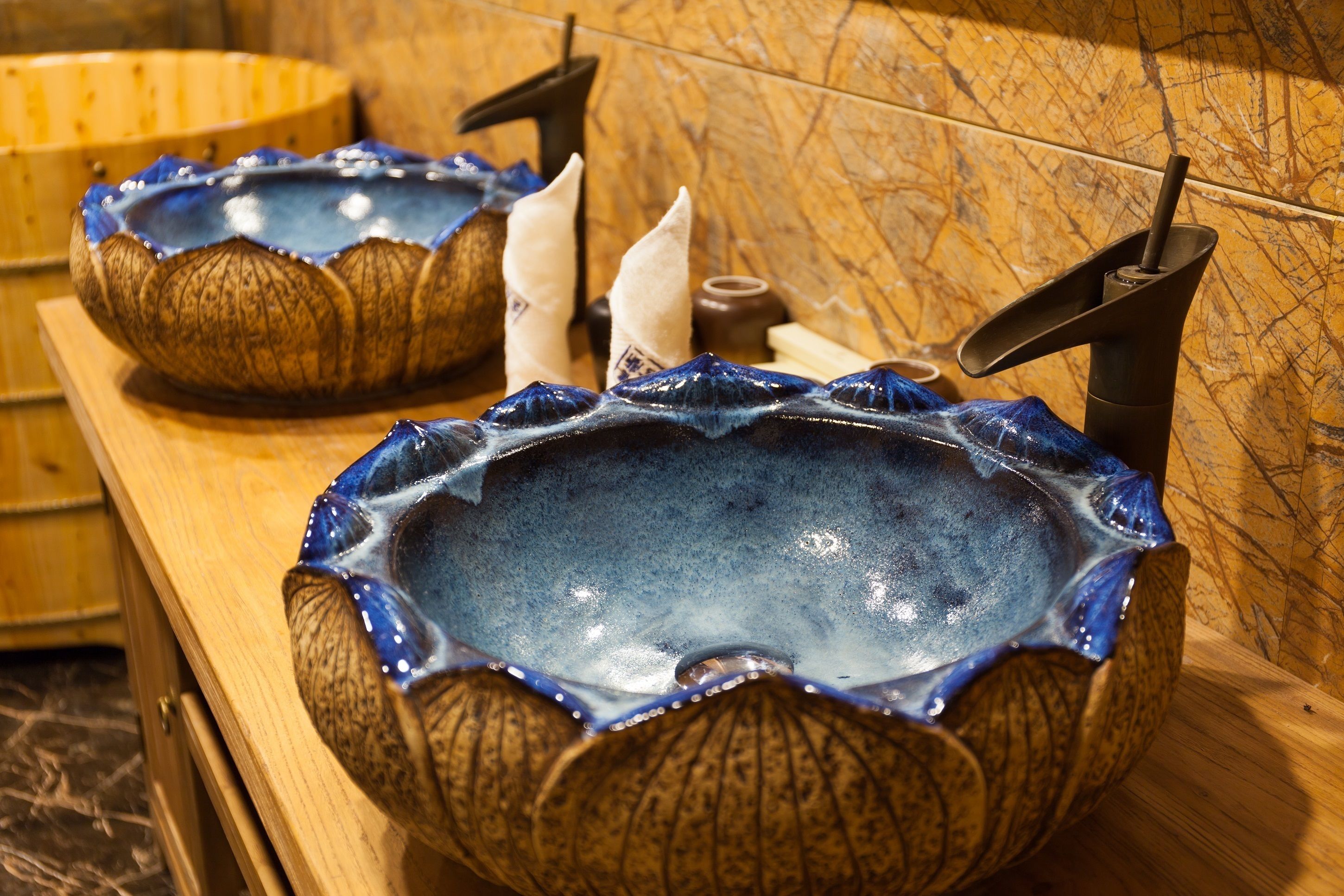 Two ceramic sinks with a unique design, placed on a wooden counter with a marble backsplash.