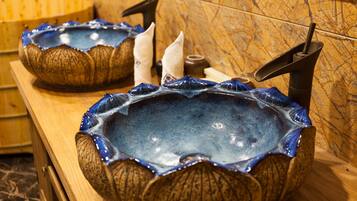 Two ceramic sinks with a unique design, placed on a wooden counter with a marble backsplash.