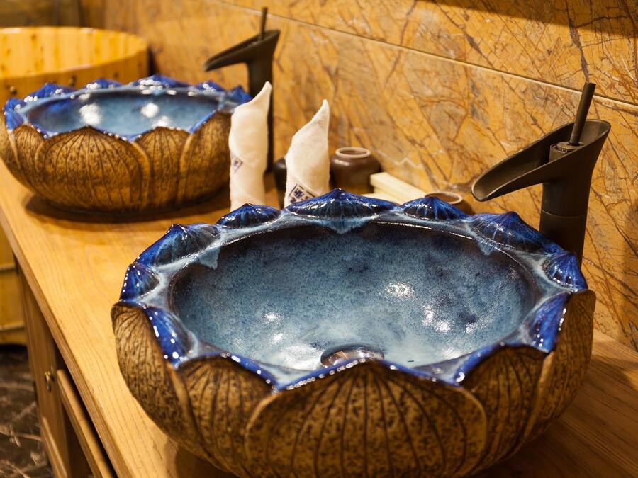 Two ceramic sinks with a unique design, placed on a wooden counter with a marble backsplash.