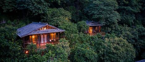 Two traditional wooden buildings nestled among dense forest.
