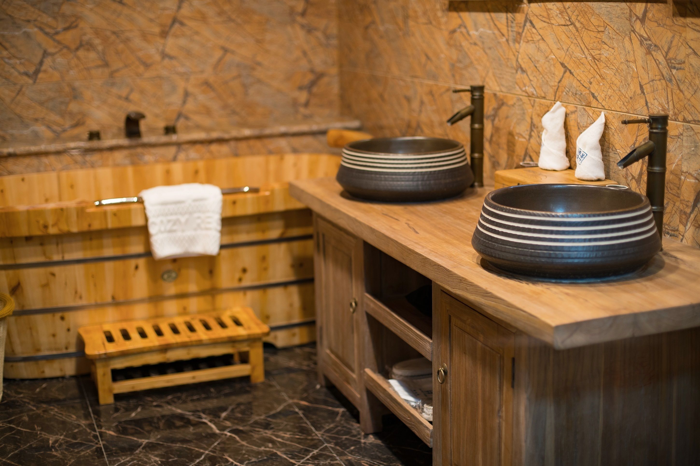 Un baño de madera con un lavabo grande, un perchero para toallas y un banco de madera.