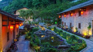 A traditional courtyard with a stone bridge, a small pond, and buildings with tiled roofs and lanterns. - Yangshuo Ancient Garden Boutique Hotel (Guilin)