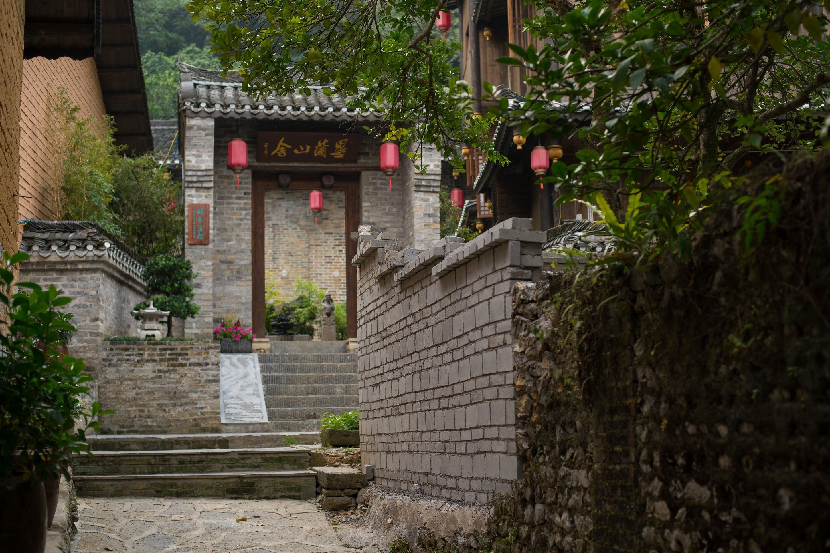 A traditional Chinese courtyard with stone steps leading to a wooden gate.