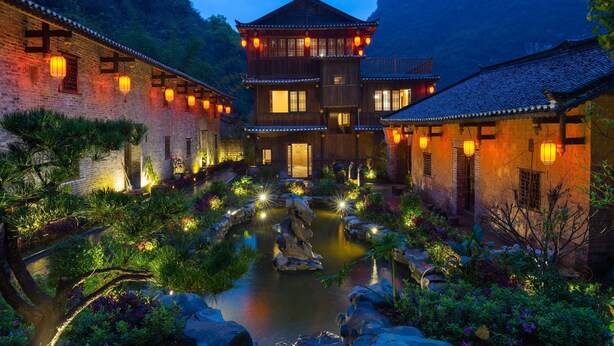A traditional Chinese courtyard with a central pond, surrounded by brick buildings with wooden balconies and lanterns. - Yangshuo Ancient Garden Boutique Hotel (Guilin)