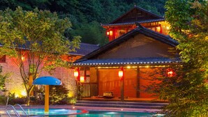 A traditional building with a pool, surrounded by trees and illuminated by warm lights. - Yangshuo Ancient Garden Boutique Hotel (Guilin)