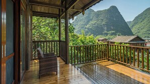 A wooden deck with a wicker chair, overlooking a mountainous landscape with traditional buildings. - Yangshuo Ancient Garden Boutique Hotel (Guilin)