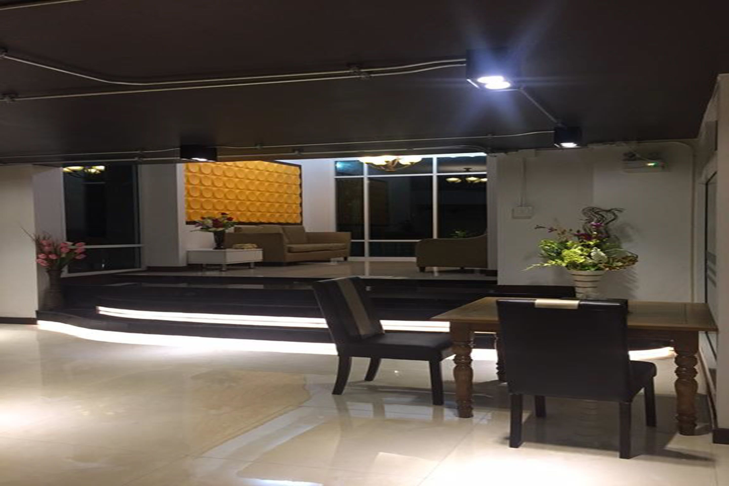 Un interior moderno con zona de comedor que incluye una mesa y sillas de madera, un sofá y una pared de acento amarilla.