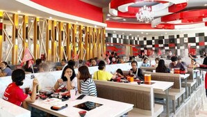 A modern restaurant with red and white decor, multiple dining tables, and a variety of dishes. - Leelawadee Resotel Raminthra 23 (Bangkok)