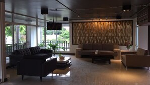 A modern lobby with a sectional sofa, a coffee table, and a decorative wall. - Leelawadee Resotel Raminthra 23 (Bangkok)