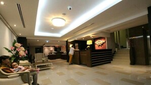 A hotel lobby with a reception desk, seating area, and a staircase. - Leelawadee Modern Resort Huaykwang (Bangkok)