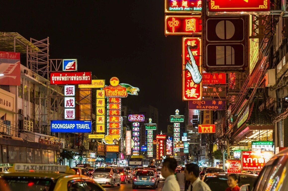 A busy street at night with illuminated signs in multiple languages, including a prominent 'SEAFOOD' sign.