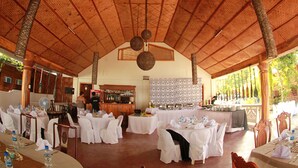 A covered outdoor dining area with tables set for a meal, a bar area, and a patterned wall in the background. - Pandan Beach Resort (Pandan)