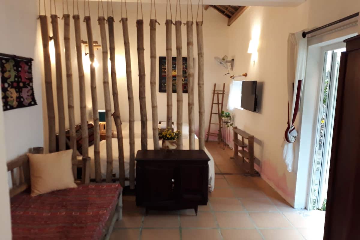 Una habitación con cama, una mesita, un televisor instalado en la pared y una puerta corredera que da a otra zona.