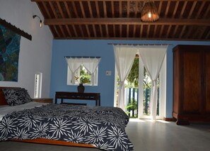 A bedroom with a bed, a nightstand, a window with curtains, a wooden ceiling, and a view of the outside. - La Terrazza (Da Nang)