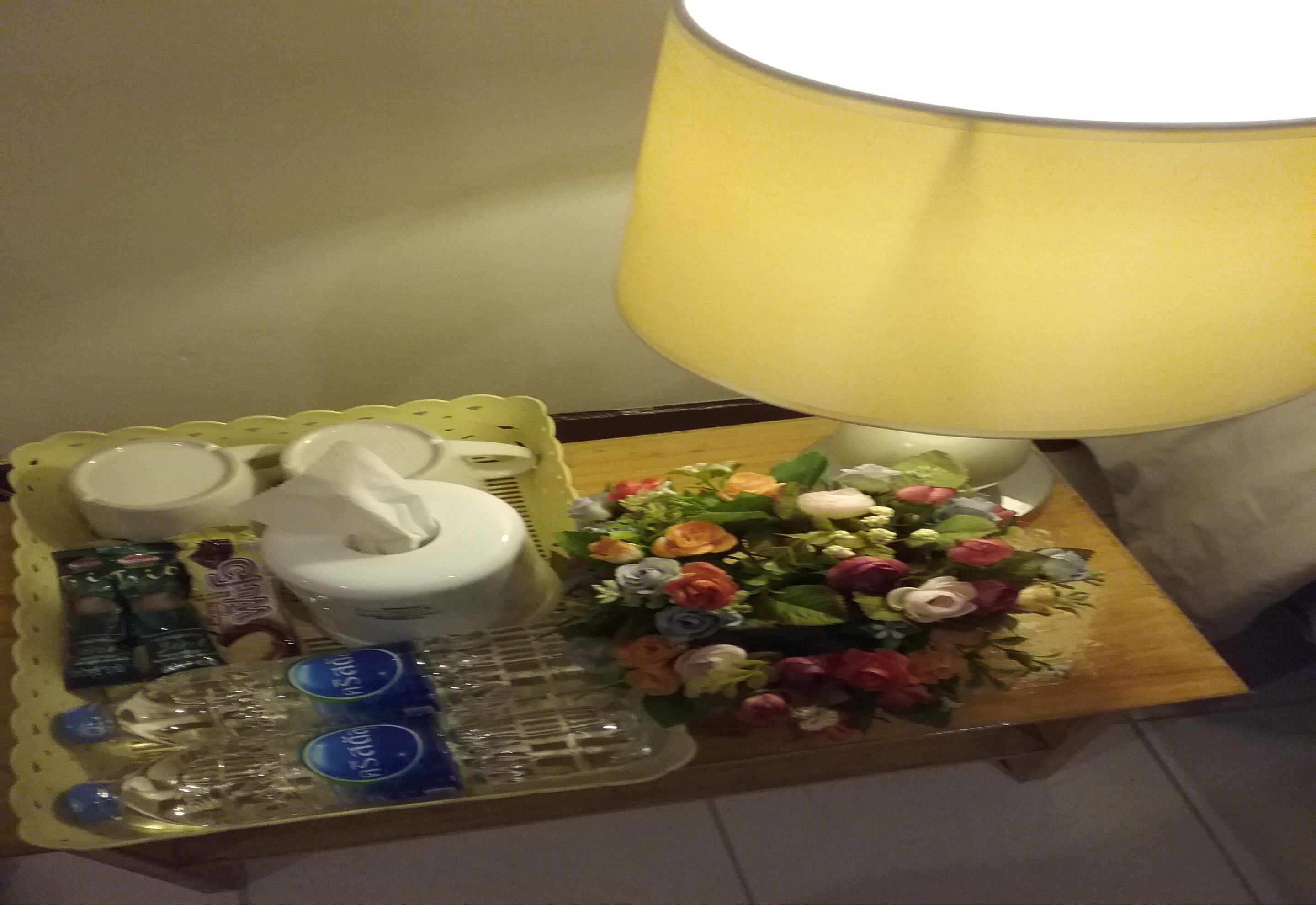 A tray with toiletries, a tissue box, and a bouquet of flowers on a wooden table.