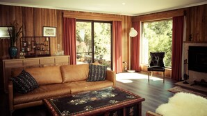 A cozy living room with a brown leather sofa, a wooden coffee table with floral designs, and a fireplace. - The Hobart Entrance (Kingston)