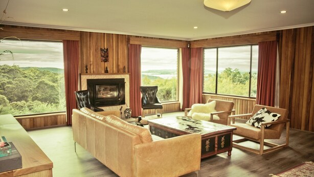 A spacious living room with a fireplace, leather sofas, and large windows offering a view of the outdoors. - The Hobart Entrance (Kingston)