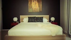 A bedroom with a large bed, dark walls, and a painting above the bed. - The Hobart Entrance (Kingston)
