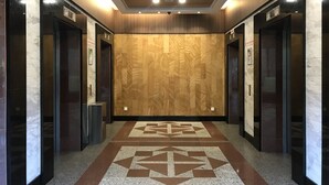 Ein moderner Aufzug mit einem geometrischen Fußbodenmuster und Holzvertäfelungen.
