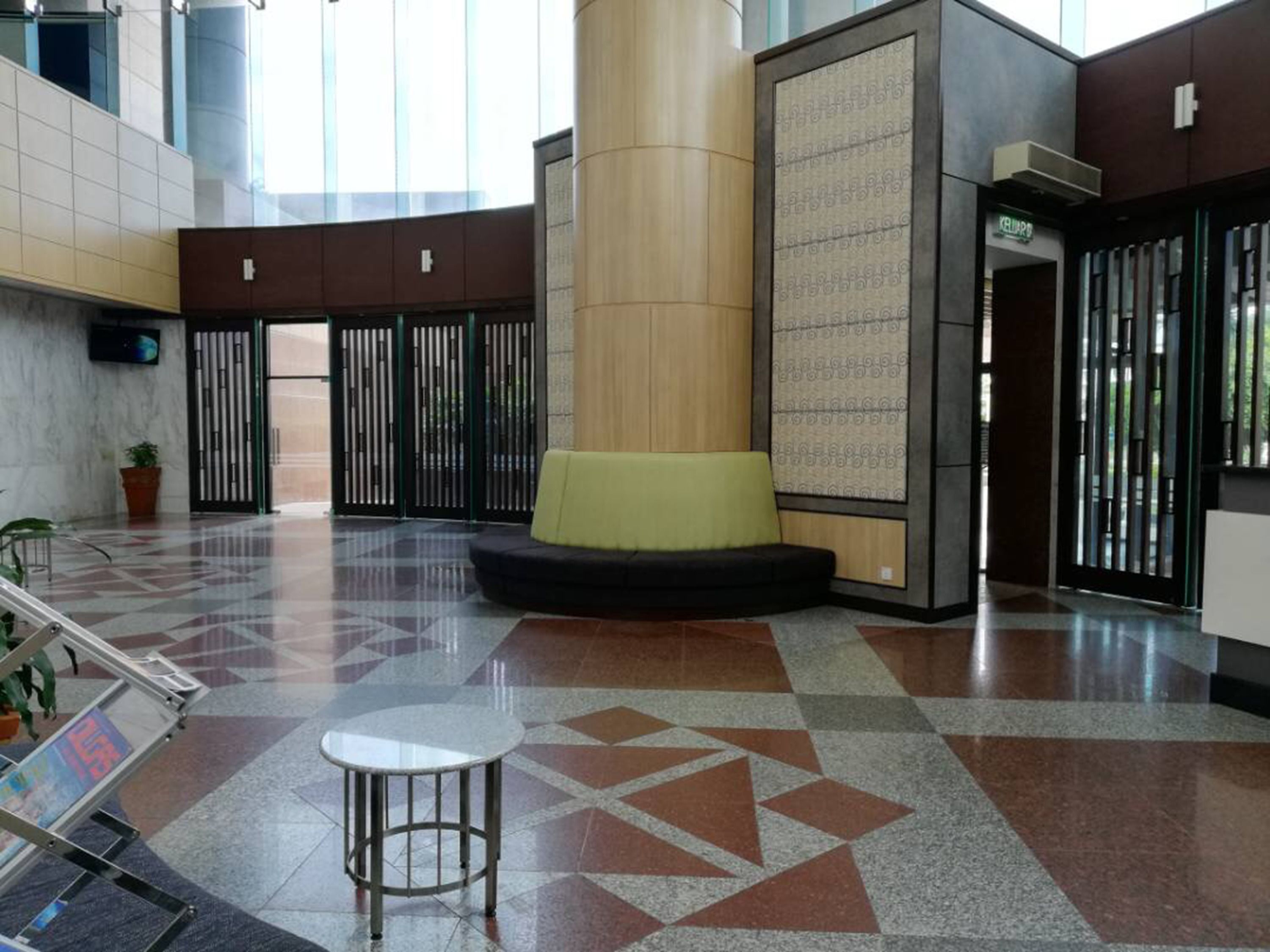 A spacious lobby with a central seating area, a staircase, and a patterned floor.