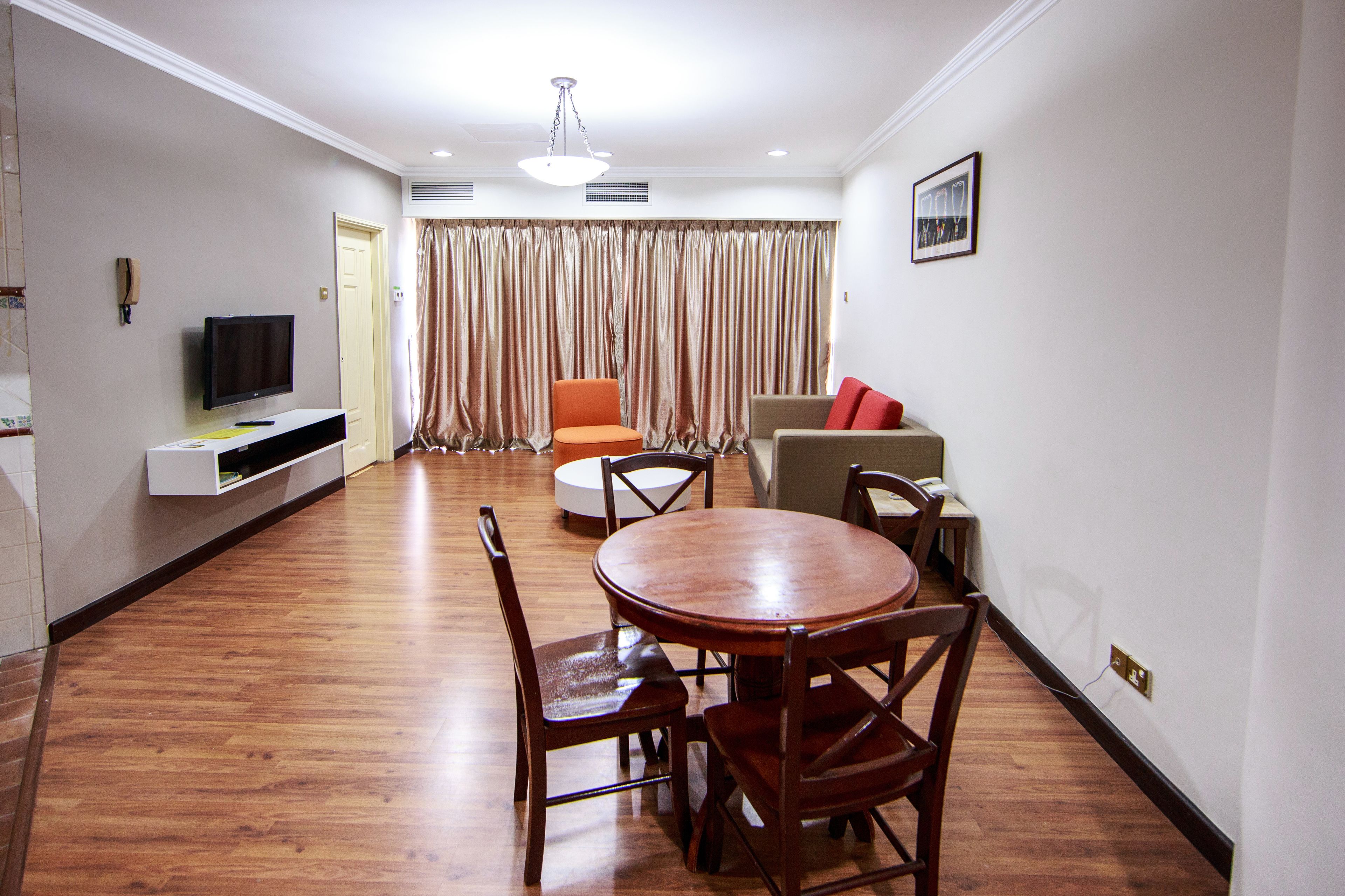 A modern living room with a wooden dining table, two chairs, a sofa, and a television.