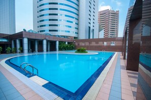 A swimming pool with a tiled deck, surrounded by modern buildings.