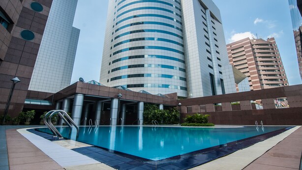 Ein modernes Hotel mit Schwimmbad, umgeben von Hochhäusern.